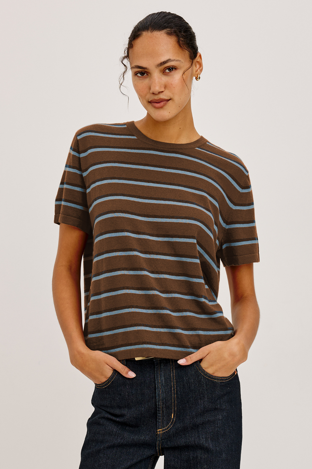 Woman wearing a brown and blue striped t-shirt against a plain background