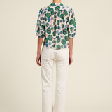Person wearing a floral blouse and white pants on a plain background