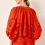 Woman wearing a red embroidered outfit on a beige background