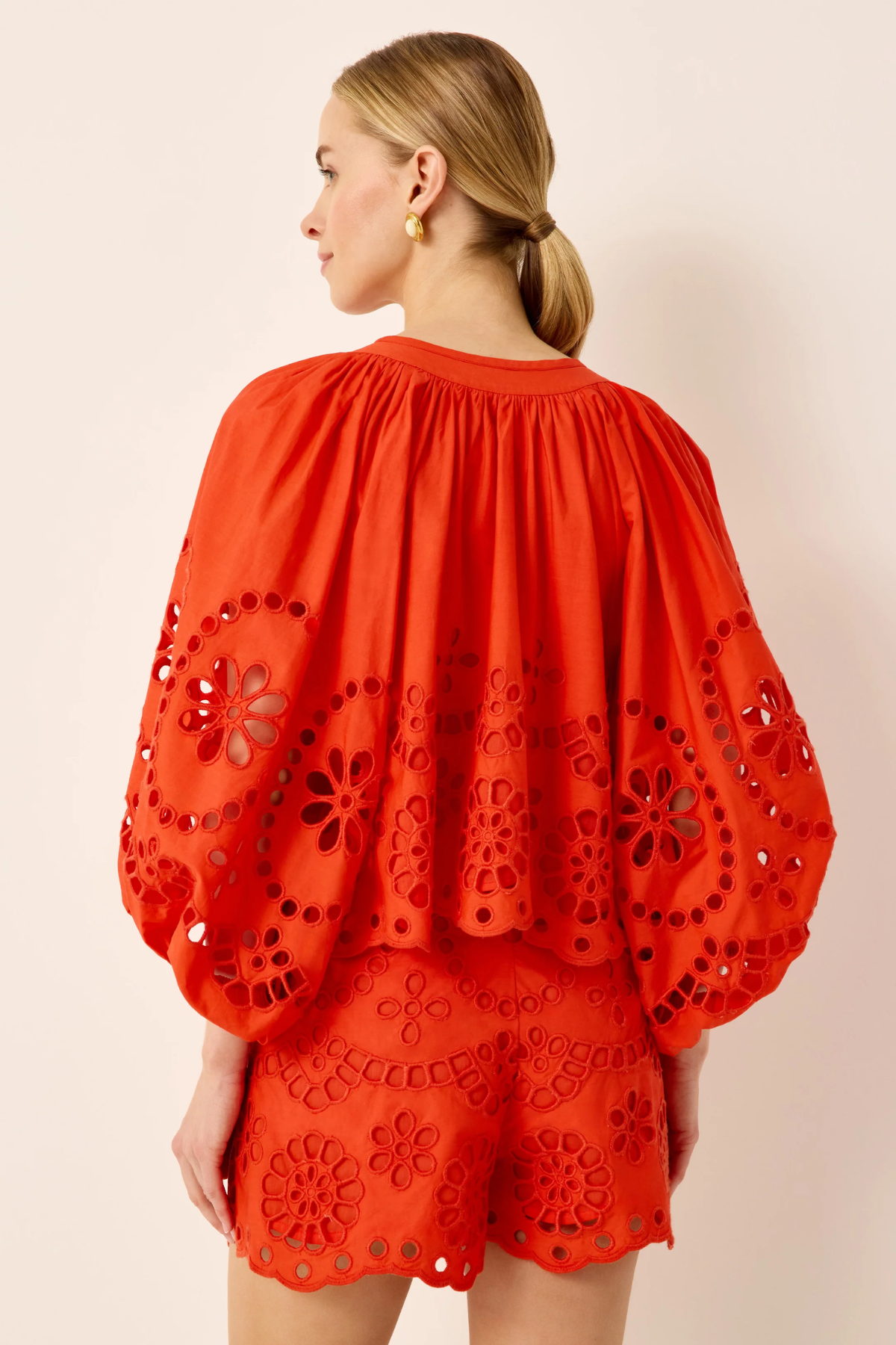 Woman wearing a red embroidered outfit on a beige background