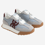 A pair of low-top sneakers in light gray suede and synthetic materials, featuring white laces, a white midsole, a brown gum outsole, and a dark brown 'GG' logo on the side.