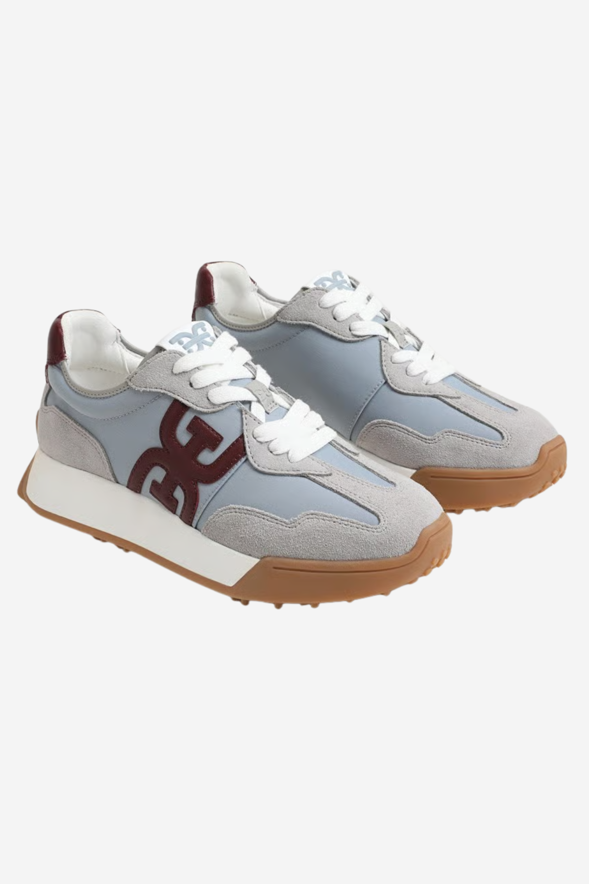 A pair of low-top sneakers in light gray suede and synthetic materials, featuring white laces, a white midsole, a brown gum outsole, and a dark brown 'GG' logo on the side.