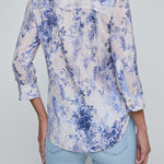 Person wearing a blue floral shirt and light blue jeans on a gray background