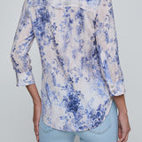 Person wearing a blue floral shirt and light blue jeans on a gray background
