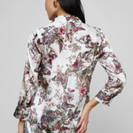 Woman wearing a floral blouse with long sleeves on a gray background