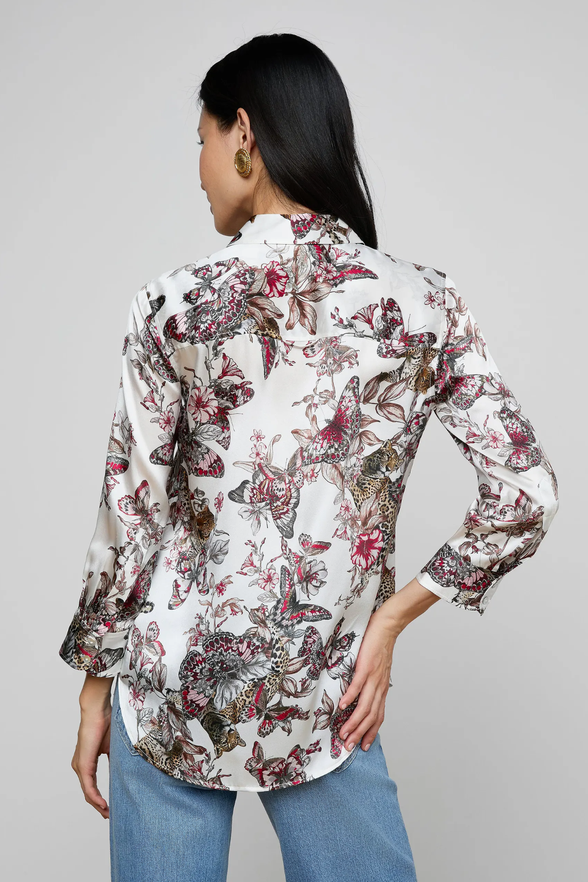 Woman wearing a floral blouse with long sleeves on a gray background
