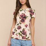 Woman wearing a floral top and denim shorts against a beige background