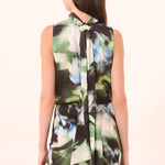 Woman wearing a sleeveless dress with a floral pattern on a beige background