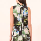 Woman wearing a sleeveless dress with a floral pattern on a beige background