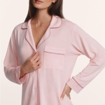 Woman wearing a pink pajama set against a light pink background