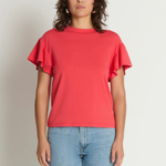 Woman wearing a red ruffled sleeve top and blue jeans against a plain background