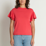Woman wearing a red ruffled sleeve top and blue jeans against a plain background
