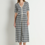 Woman wearing a black and white striped dress against a plain background