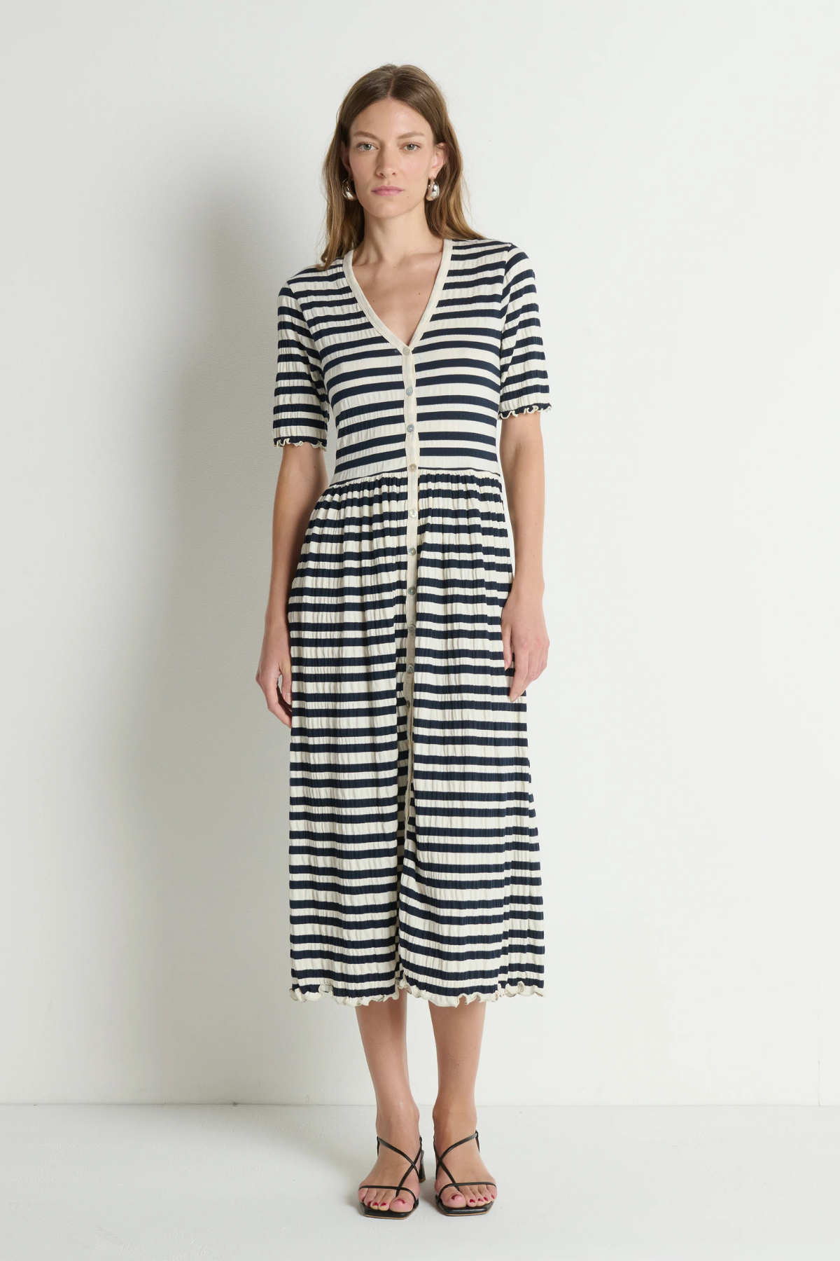 Woman wearing a black and white striped dress against a plain background