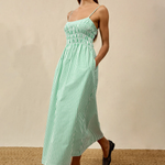 Woman wearing a green striped dress against a beige background
