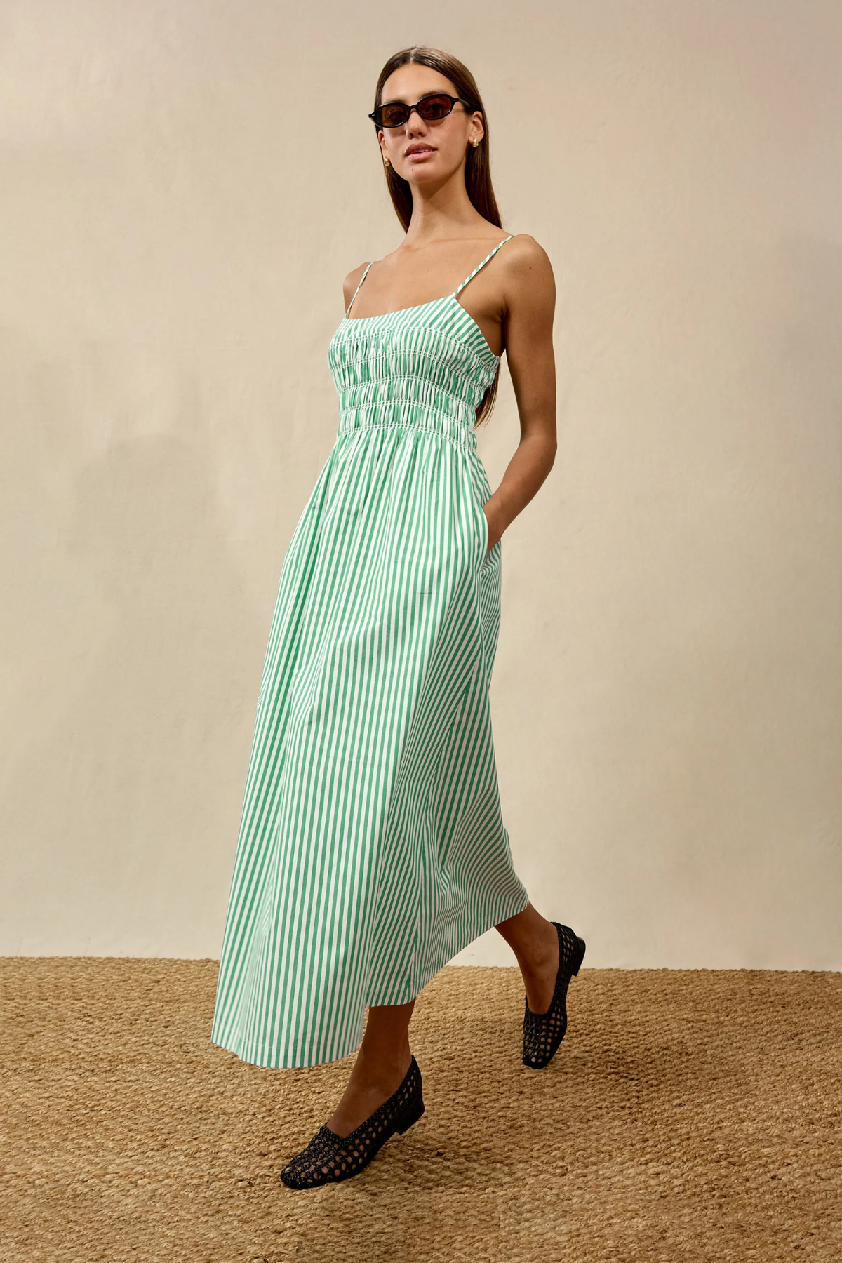 Woman wearing a green striped dress against a beige background