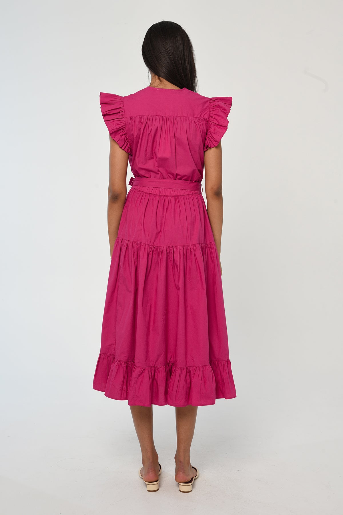 Woman wearing a vibrant pink sleeveless midi dress with soft tailoring and fluid drape.