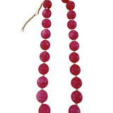 A chunky beaded necklace featuring large, glossy round magenta-pink beads separated by small gold spacer beads, with a gold-tone clasp and extender chain, shown on a plain white background.