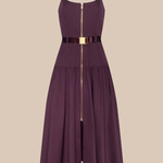 A sleeveless midi dress in deep plum purple with a thin black belt at the waist featuring a gold buckle, and a central gold zipper running down the front. The dress has thin shoulder straps and a tiered skirt, shown against a solid beige background.