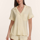 Woman wearing a light yellow pajama set on a beige background