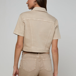 Woman wearing a beige jacket and pants on a plain background