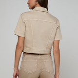 Woman wearing a beige jacket and pants on a plain background