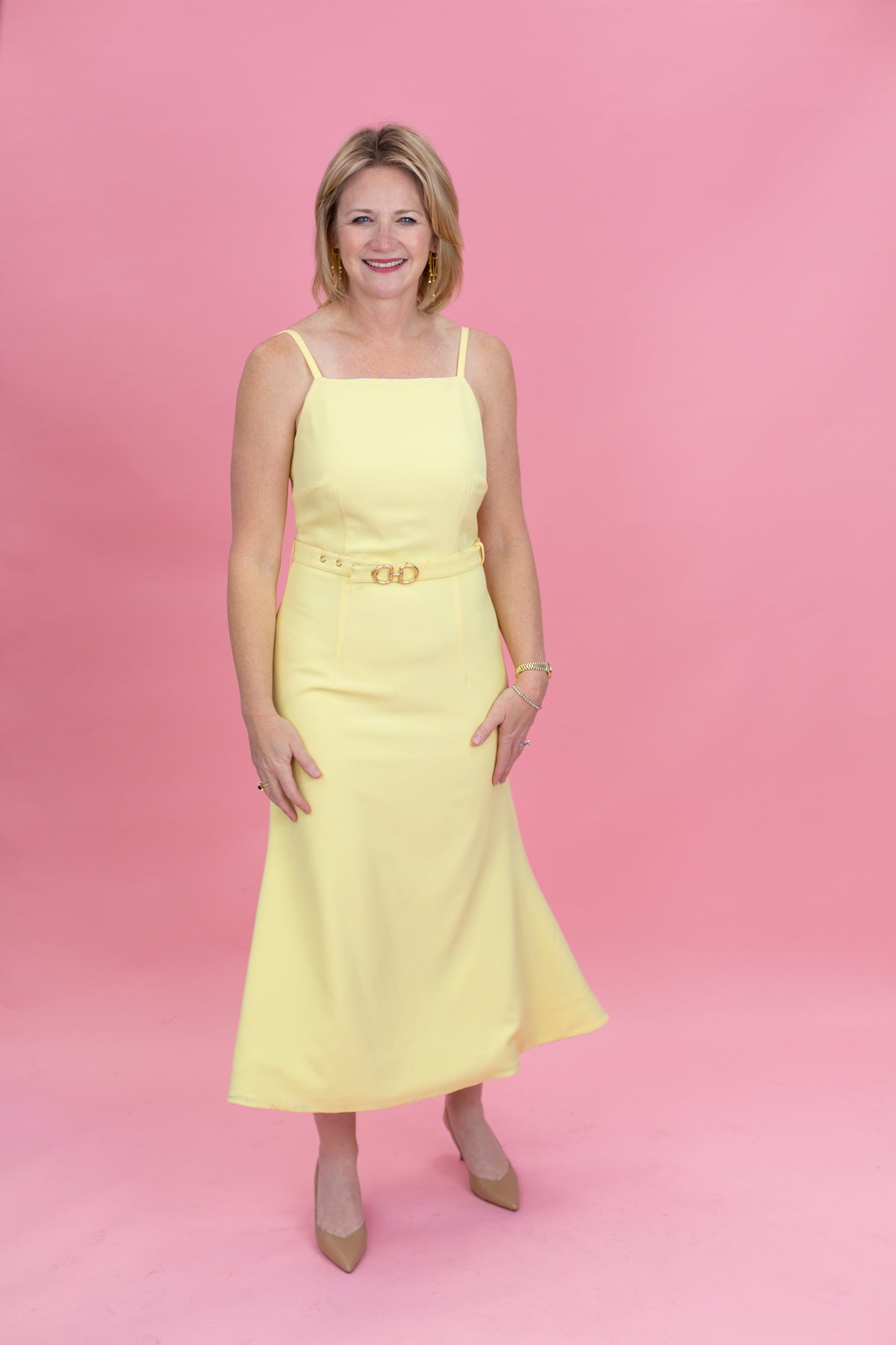 Woman wearing a yellow dress against a pink background
