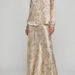 Woman wearing a beige patterned outfit on a plain background