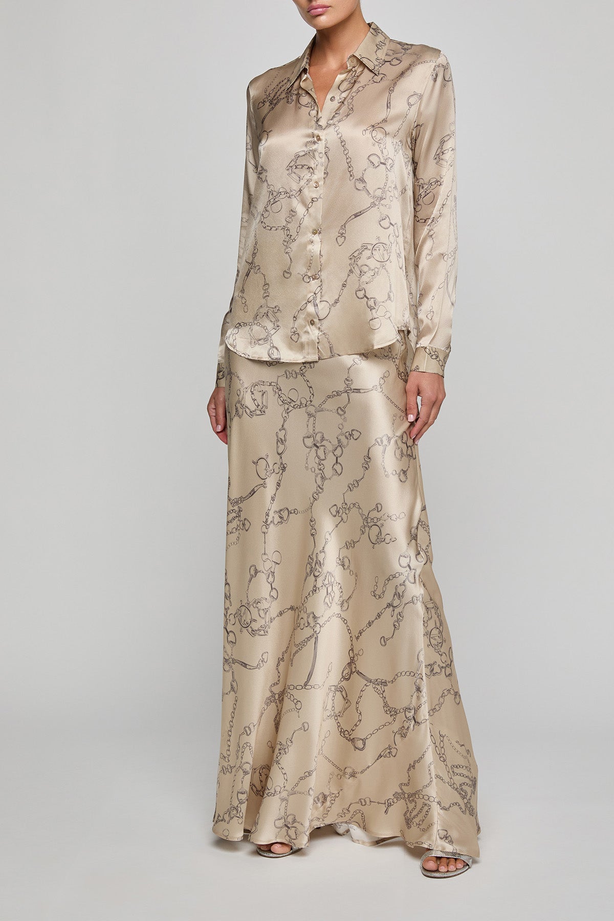 Woman wearing a beige patterned outfit on a plain background