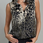 A woman wearing a sleeveless button-front blouse with a black and beige animal print pattern, paired with dark jeans, against a plain gray studio background.