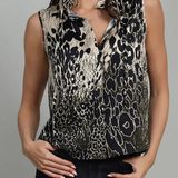 A woman wearing a sleeveless button-front blouse with a black and beige animal print pattern, paired with dark jeans, against a plain gray studio background.