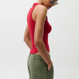 Woman wearing a red sleeveless top and green cargo pants against a white background
