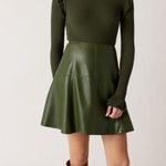 Person wearing a green ribbed sweater and leather skirt with brown knee-high boots on a white background