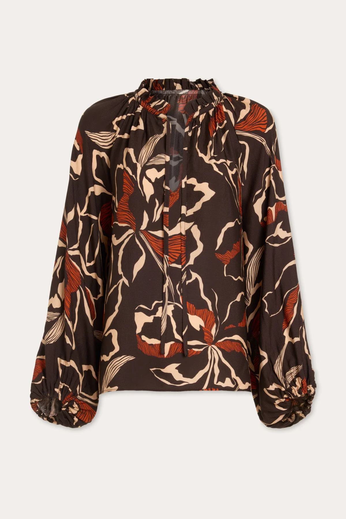 A long-sleeve blouse with a brown base and an abstract floral pattern in beige and rust orange, featuring a tie-neck detail and gathered cuffs, shown against a light gray background.