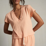 Woman wearing a peach-colored outfit against a plain background