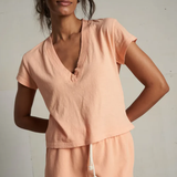 Woman wearing a peach-colored outfit against a plain background