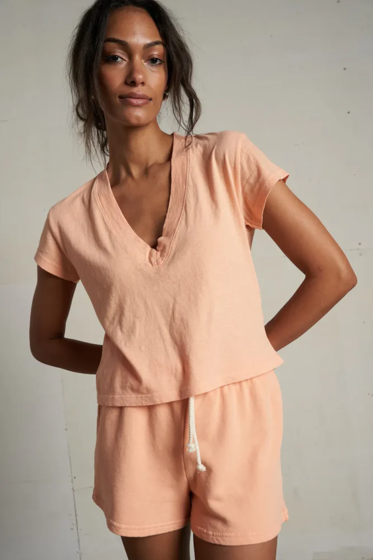 Woman wearing a peach-colored outfit against a plain background