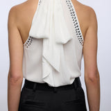 White halter top with black embellishments and black pants on a white background