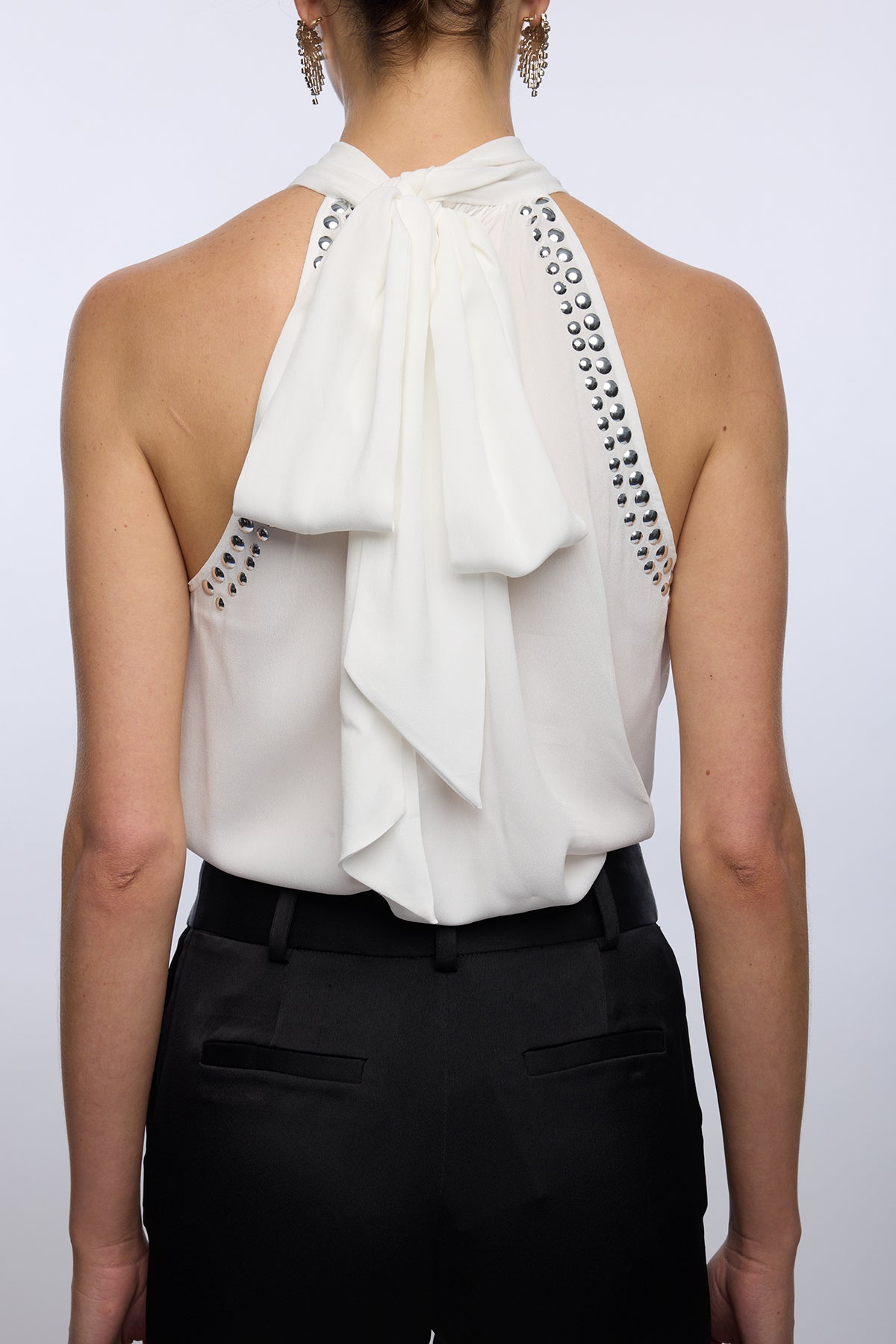 White halter top with black embellishments and black pants on a white background