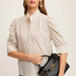Woman holding a black handbag against a plain background