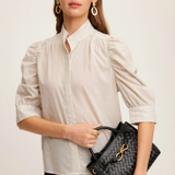 Woman holding a black handbag against a plain background