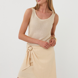 Woman wearing a beige sleeveless top and skirt on a white background