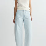Person wearing a white tank top and light blue pants on a plain background