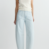 Person wearing a white tank top and light blue pants on a plain background
