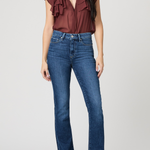 Woman wearing a burgundy ruffled top and blue jeans on a white background