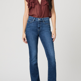 Woman wearing a burgundy ruffled top and blue jeans on a white background