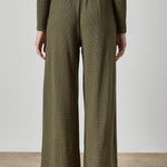 Person wearing olive green ribbed pants and top on a plain background