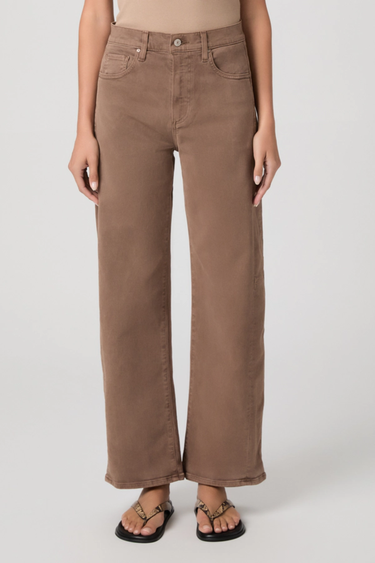 Person wearing brown wide-leg jeans on a plain background