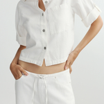 Person wearing a white button-up shirt and pants on a light gray background