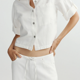 Person wearing a white button-up shirt and pants on a light gray background